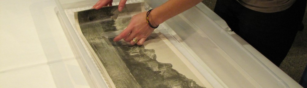 Image showing Lisa Duncan's hands performing a wet treatment on a long narrow artwork on paper in a plastic basin