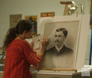 Small image showing Lisa Duncan conserving an artwork on an easel in a conservation lab