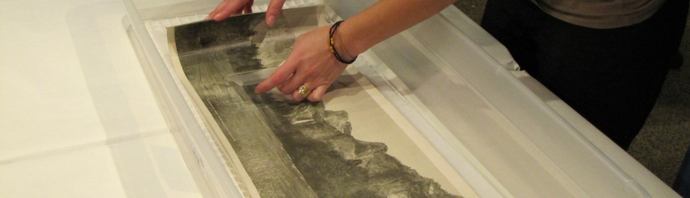 Image showing Lisa Duncan's hands performing a wet treatment on a long narrow artwork on paper in a plastic basin